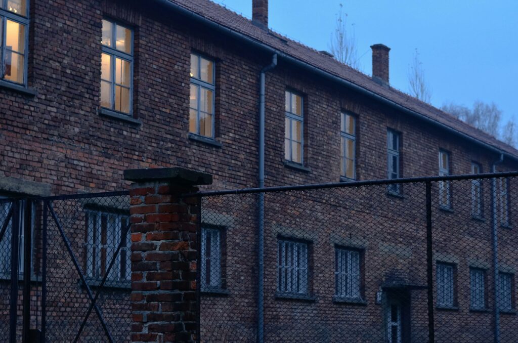 A brick building with a fence at Auschwitz concentration camp during the day.